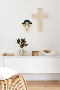 a white room with a cross on the wall and some plants in front of it