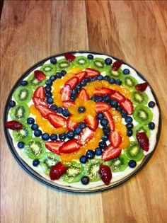 a plate with fruit arranged in the shape of a spiral on top of a wooden table