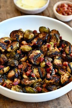 a white bowl filled with brussel sprouts on top of a wooden table