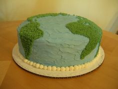 there is a cake that looks like the earth on it's side, with green grass and white icing