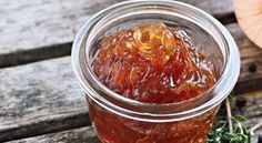 a glass jar filled with jelly sitting on top of a wooden table next to an orange pumpkin