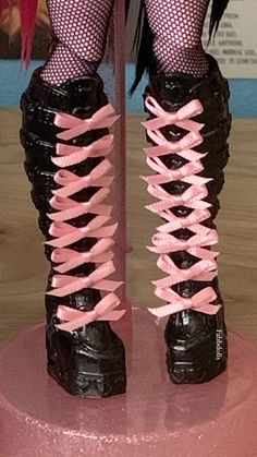 a close up of a person's legs wearing black boots with pink laces