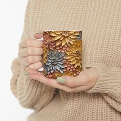 a woman is holding a coffee mug with flowers on the front and sides in her hands