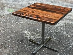 a wooden table sitting on top of a metal stand in the middle of a parking lot