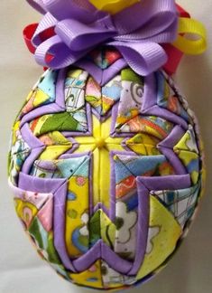 an ornament made to look like a ball with purple ribbon on top and yellow base