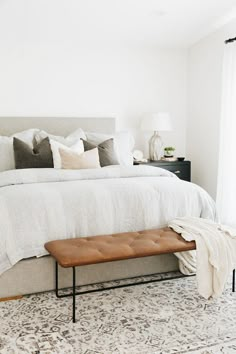 a bedroom with a large bed, white walls and rugs on the floor next to it