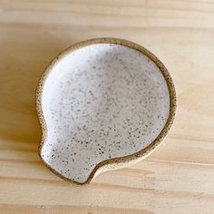 a white and brown speckled dish on a wooden surface