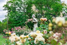 a garden with flowers and a statue in the middle