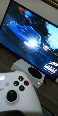 a close up of a video game controller and a television screen with the image of a racing car on it