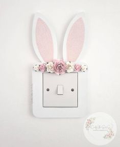 a white light switch with pink flowers and bunny ears on it's face, attached to a wall