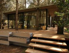 a wooden deck in front of a house surrounded by trees