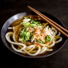 a bowl filled with noodles and vegetables next to chopsticks