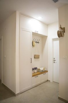 an empty room with white walls and cupboards on the wall, two clocks hanging from hooks