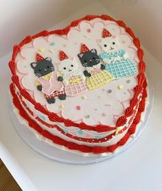 a heart shaped cake decorated with cats and other decorations on top of a white plate