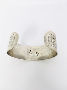 "This gorgeous cuff bracelet is rendered in sterling silver and features a beautiful flower and leaf design. It measures 1 1/4\" wide and I believe dates to around 1940. It is marked Sterling on the inside along with several other markings that would appear to either be bird prints or possibly arrows. Unfortunately my efforts to find out any further information have been unsuccessful. It's truly a lovely piece. Weighs approximately 32.7 grams. I have many beautiful period antique pieces in my sh Vintage Stamped Cuff Bracelet For Wedding, Stamped Sterling Silver Cuff Bracelet For Wedding, Sterling Silver Stamped Cuff Bracelet For Wedding, Silver Stamped Cuff Bracelet, Silver Stamped Cuff Bracelet For Wedding, Vintage Sterling Silver Cuff Bangle, Vintage Stamped Sterling Silver Cuff Bracelet, Vintage Sterling Silver Stamped Cuff Bracelet, Vintage Sterling Silver Cuff Bracelet For Anniversary