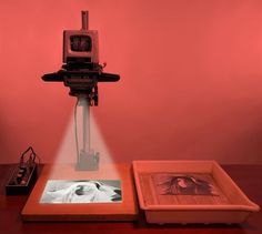 an old fashioned camera sitting on top of a wooden table next to a framed photo