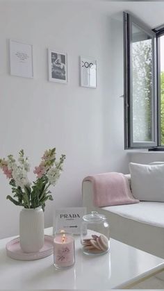 a living room with white furniture and flowers on the coffee table in front of a window