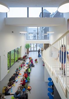 a group of children sitting on the floor in a room with white walls and stairs