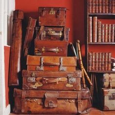 several old suitcases stacked on top of each other in front of bookshelves