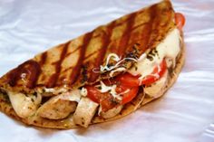 a sandwich with chicken, tomatoes and cheese on it