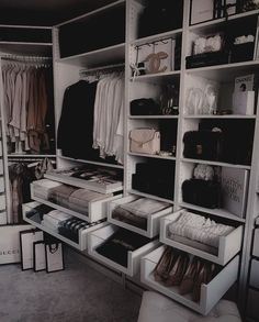 an organized closet with clothes, shoes and bags on shelves in black and white colors