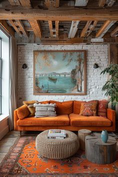 a living room with an orange couch and large painting on the brick wall above it