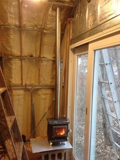 a room that is under construction with a stove in the corner and some ladders on the wall