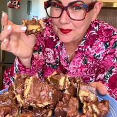 an older woman holding up a piece of chocolate covered dessert in front of her face