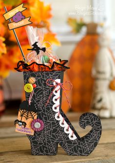 a decorated halloween boot sitting on top of a wooden table next to a vase filled with candy