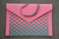 a pink envelope with a chain attached to the front and bottom, sitting on top of a gray floor