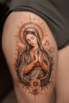 a woman's thigh with an image of the virgin mary on it and flowers