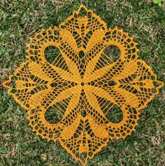 a yellow doily sitting on top of green grass