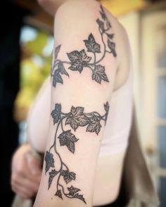 a woman's arm with vines and leaves tattooed on the left side of her arm