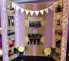 a table topped with pictures and vases filled with flowers next to a purple wall