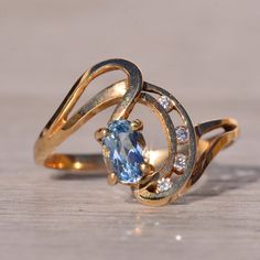 a gold ring with an oval shaped blue topazte and diamond accents