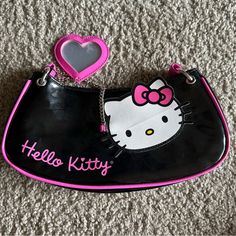 a hello kitty purse with a pink heart on the side and a black bag that says hello kitty