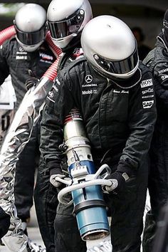 three men dressed in black and white are standing next to each other with helmets on