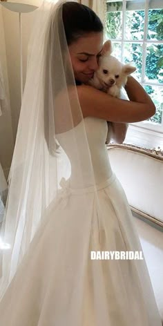 a woman in a wedding dress holding a small dog