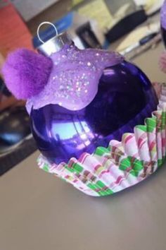 a purple ornament sitting on top of a table next to cupcakes