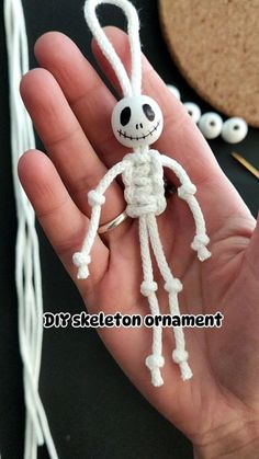 a hand holding a small white crocheted skeleton