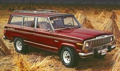 an old red jeep is parked in the middle of a field with hay bales