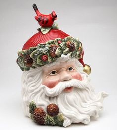 a santa claus figurine with pine cones and berries on his head, wearing a red hat