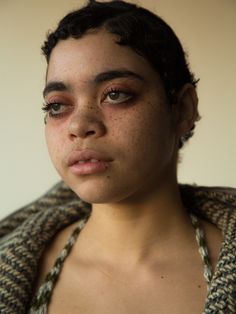 a woman with freckles on her face is looking at the camera while wearing a sweater