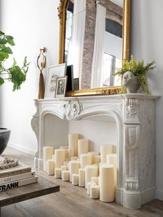 a fireplace with many lit candles in front of it and a mirror on the wall