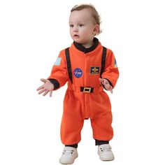 a baby in an orange astronaut suit standing with his hands out and looking at the camera