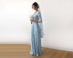 a woman in a blue wedding dress holding a bouquet and standing on a wooden floor