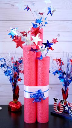 red, white and blue paper stars are on top of two pink candles with ribbons