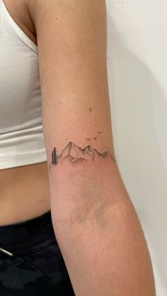 a woman's arm with a small mountain tattoo on the left side of her right arm