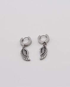 two pairs of silver hoop earrings with wings on each ear, one in the shape of an angel