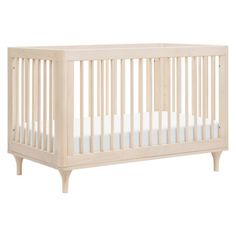 a white crib with no mattress in it on a white background, the crib is made from wood